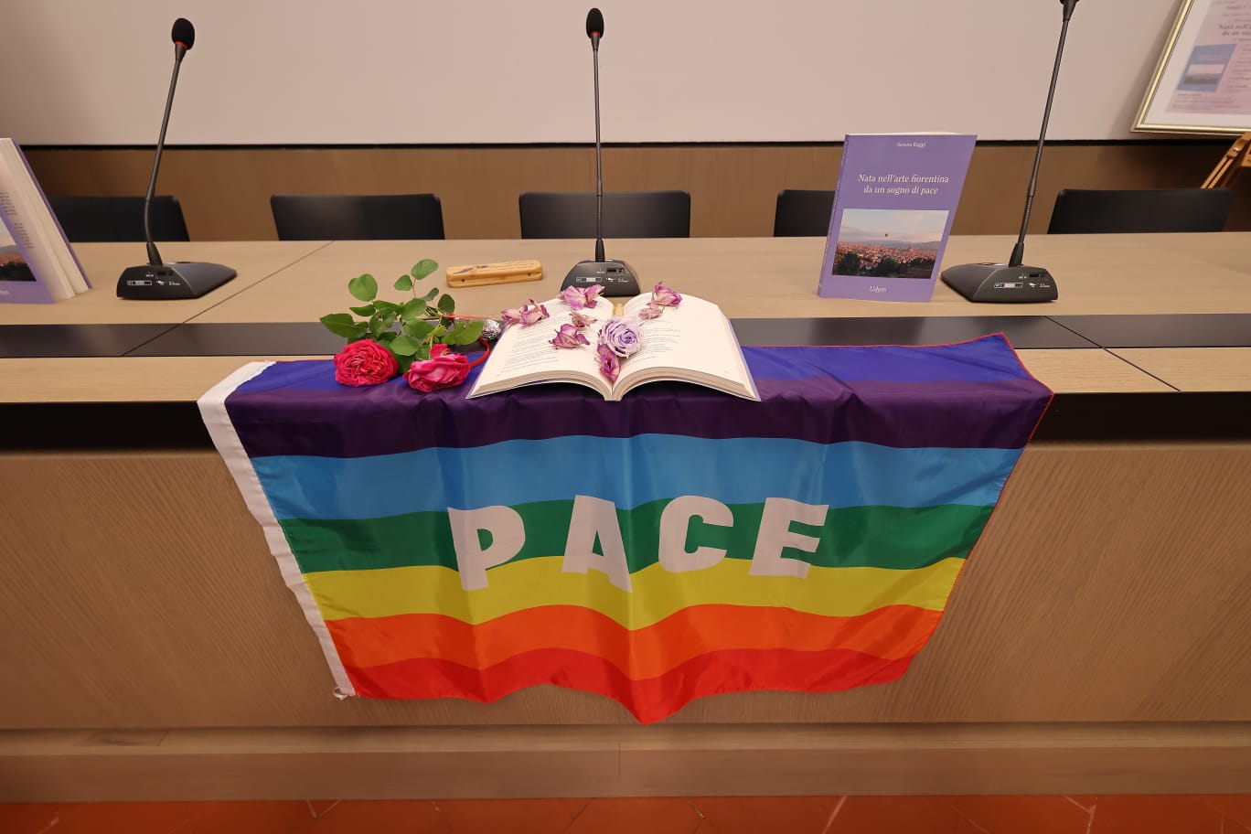 Libro di Serena Raggi, rose e bandiera della pace durante una presentazione